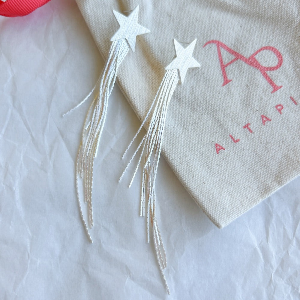 Aros de Plata Berlín con diseño de estrella satinada y finas cadenas colgantes, fabricados en acero quirúrgico bañado en plata 925, sobre bolsa de tela Altapinta.