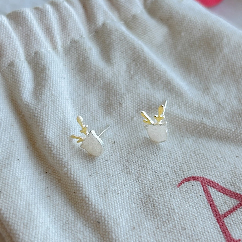 Aros de Plata Lisboa con diseño de pequeñas ramas doradas sobre base en plata 925, exhibidos sobre una bolsa de tela Altapinta.