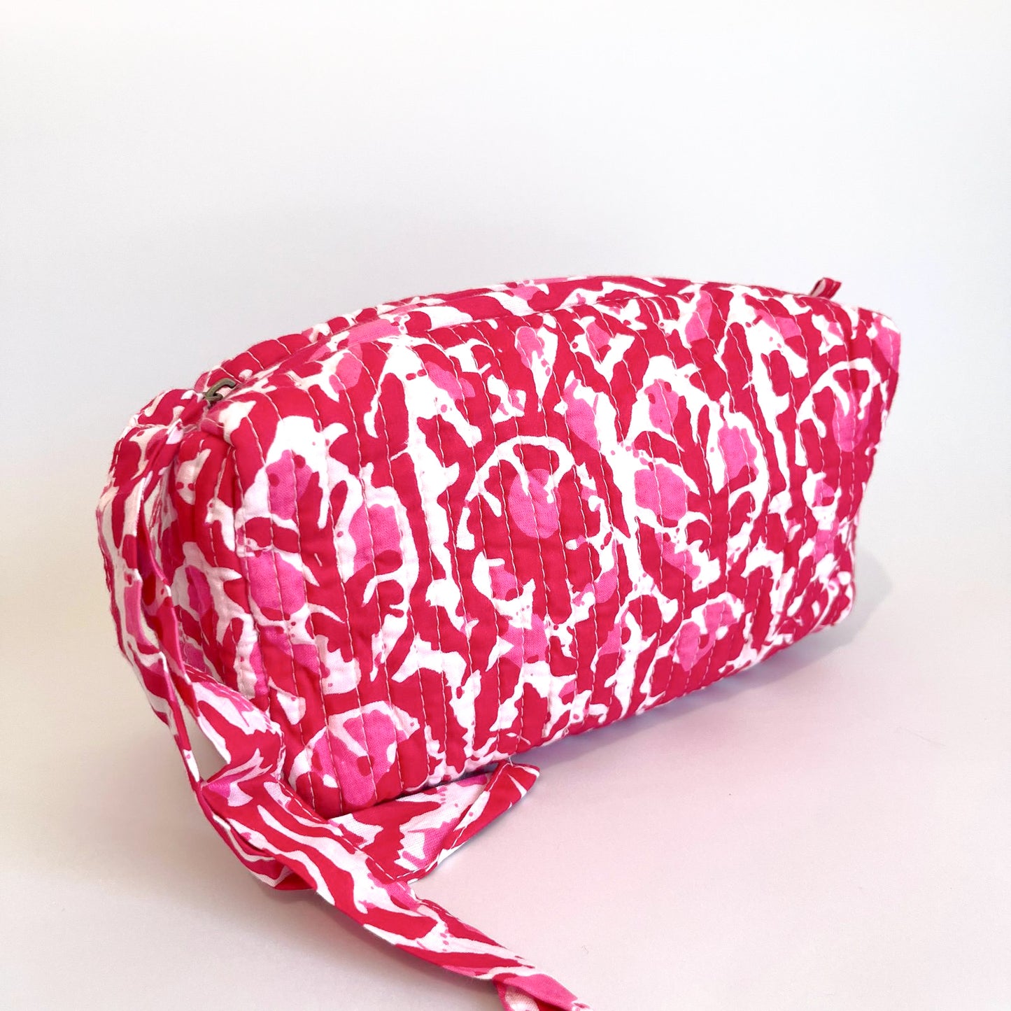 Estuche Acacia acolchado en tonos fucsia y blanco con cierre de cremallera.