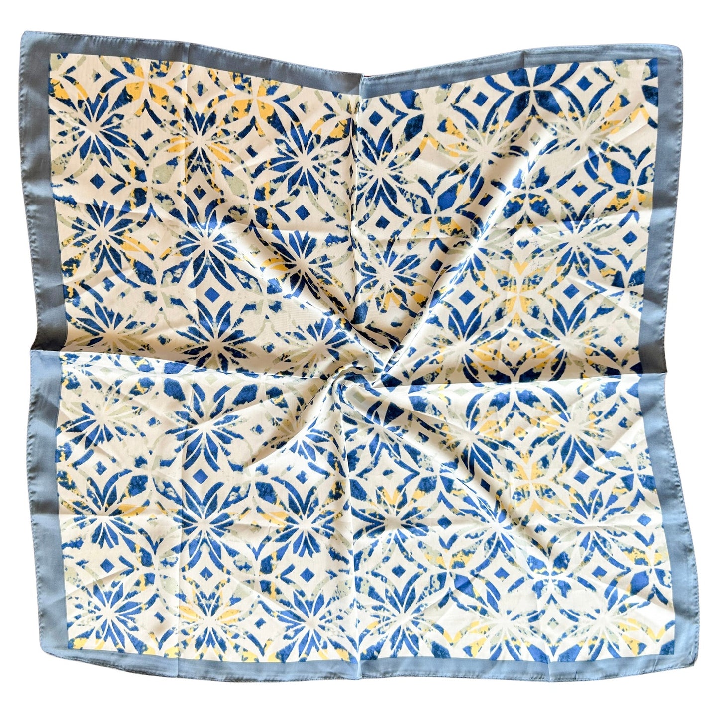 Pañuelo simil seda con estampado mediterráneo en tonos azul y amarillo, con bordes azules.