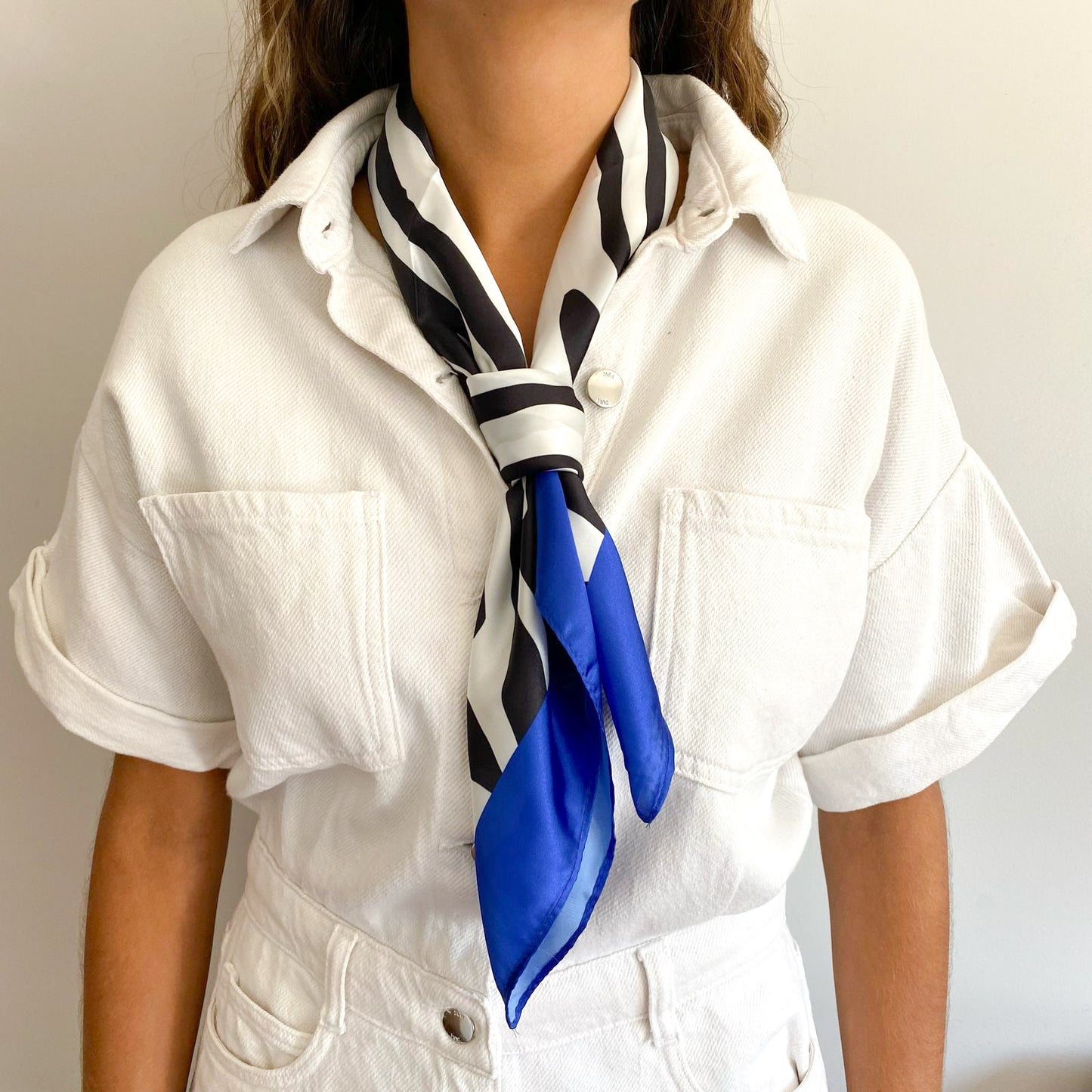 Mujer usando el pañuelo simil de seda lucca color azul amarrado en el cuello