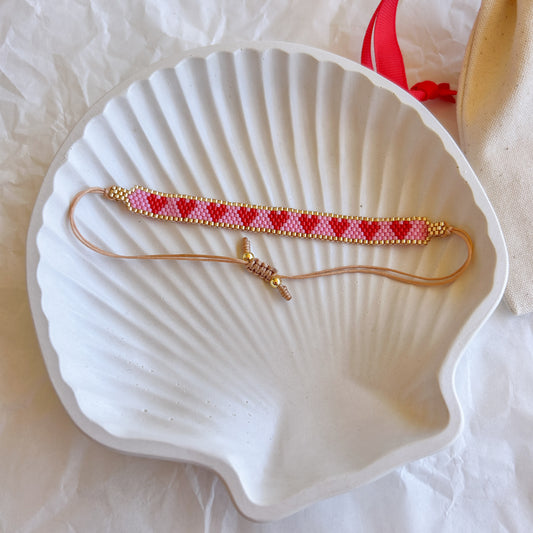 Pulsera Artesanal Corazones Josefina con corazones en tonos rojos y rosa sobre base dorada.