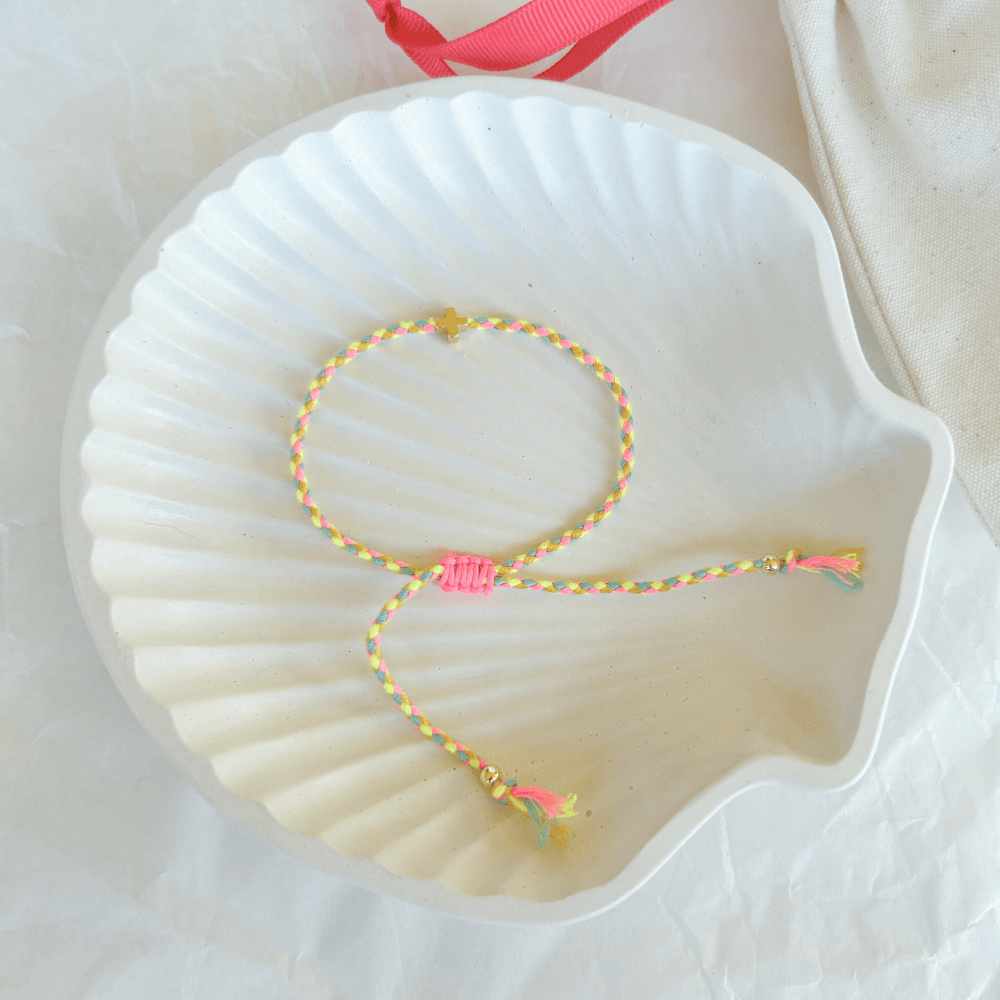 Pulsera artesanal religiosa Luisa en amarillo y rosa con hilos trenzados y cruz dorada.