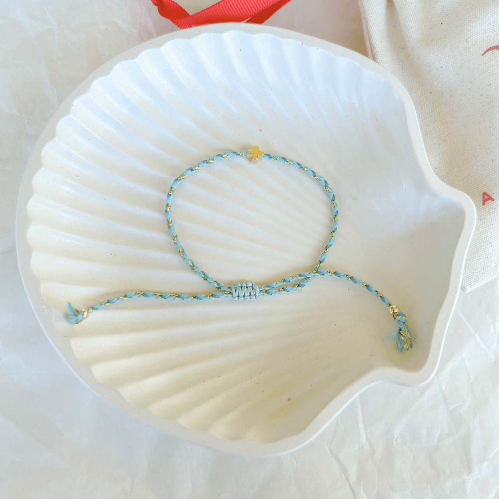 Pulsera artesanal religiosa Luisa en tonos azul y dorado con cruz central dorada.