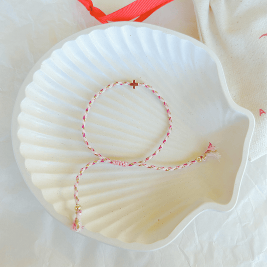 Pulsera artesanal religiosa Luisa en tonos rosa y blanco con cruz dorada.