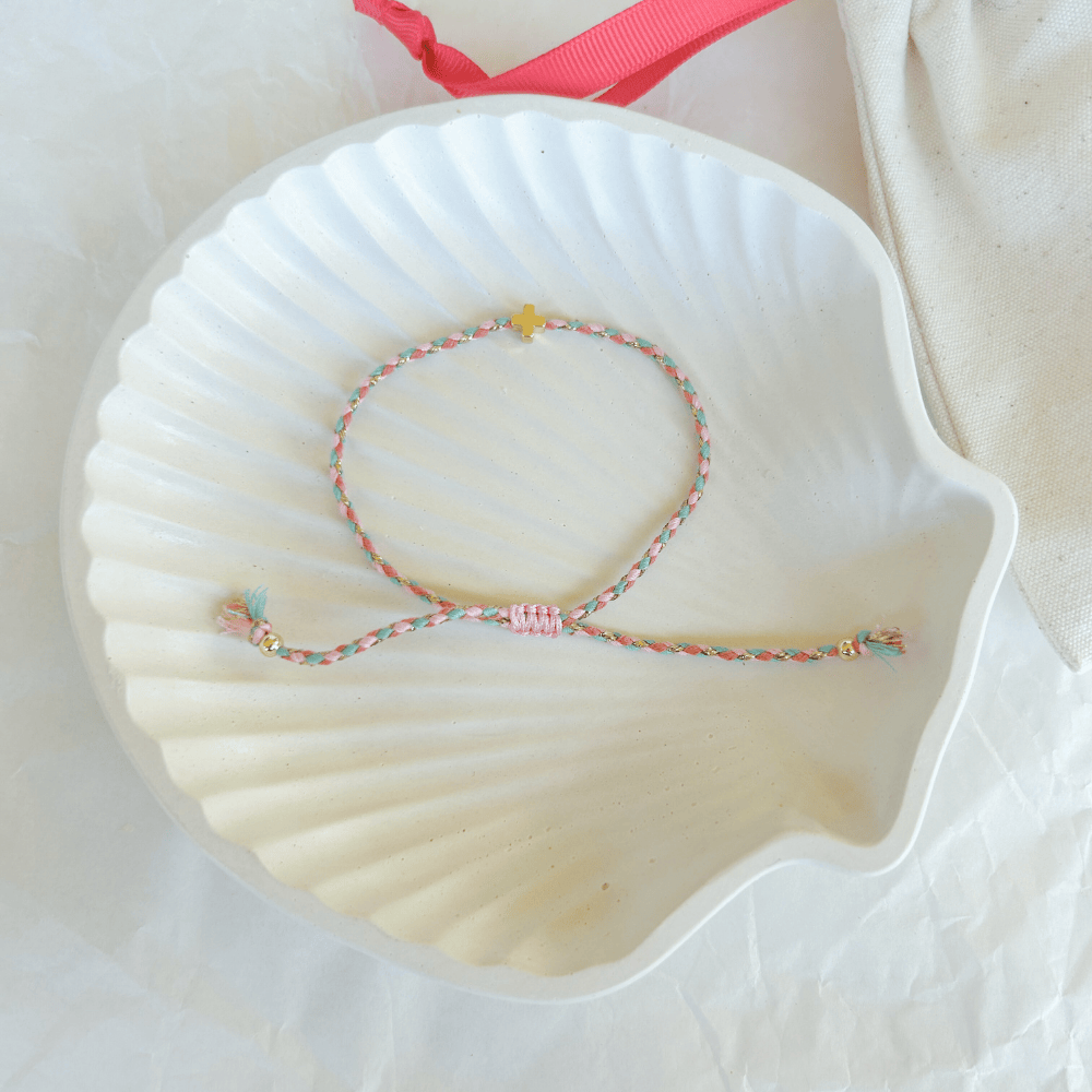 Pulsera artesanal religiosa Luisa en tonos pastel rosa y verde con cruz dorada.