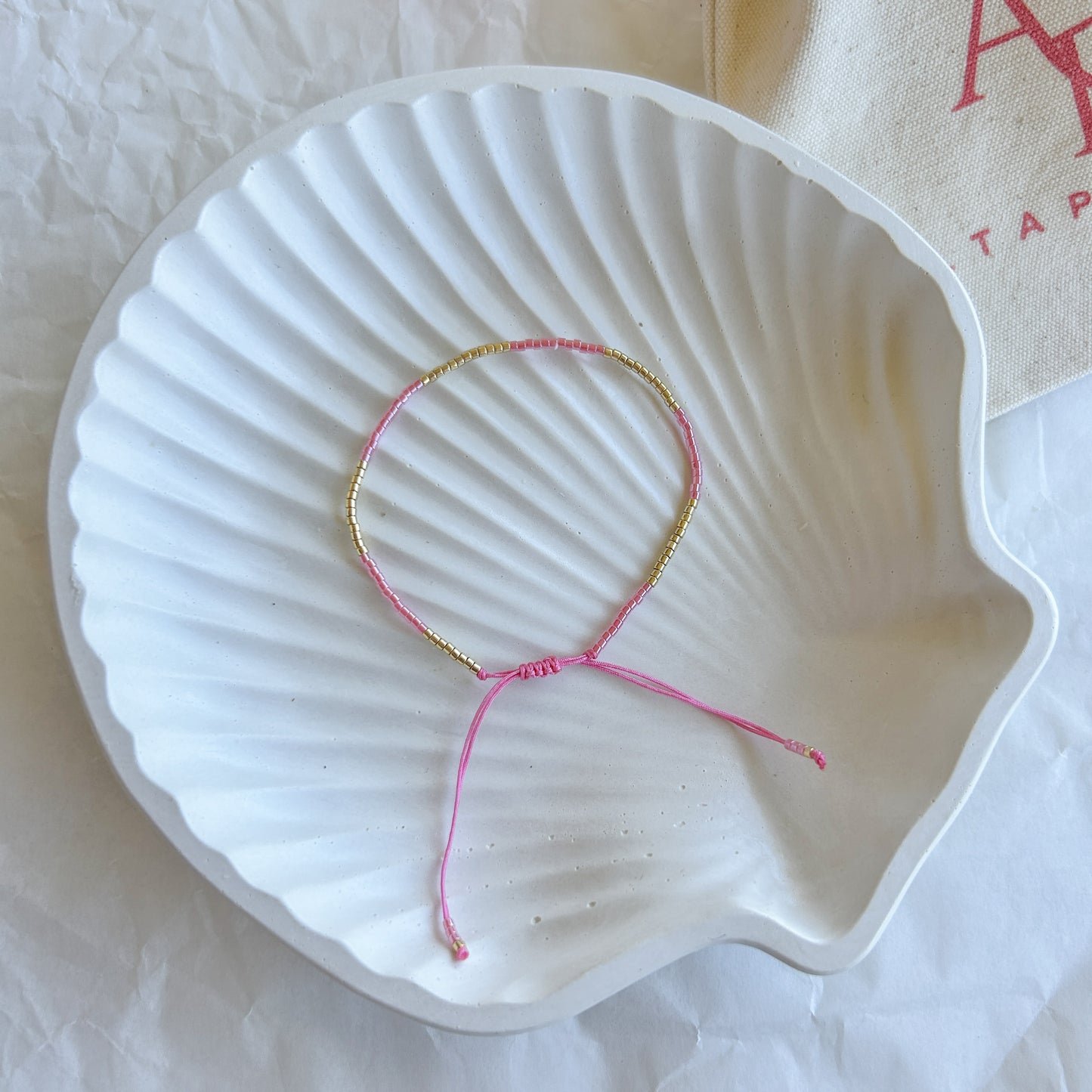 Pulsera artesanal simple Julieta color fucsia con cuentas doradas – Diseño llamativo y ajustable, ideal para quienes aman los colores vibrantes.