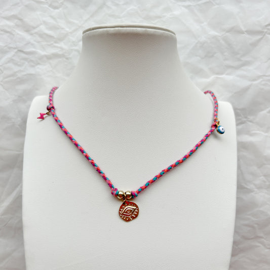 Collar Artesanal Brisa trenzado en rosa y turquesa, con dije dorado de ojo protector, cuenta de ojo turco y amuleto de rayo, exhibido en un busto blanco.