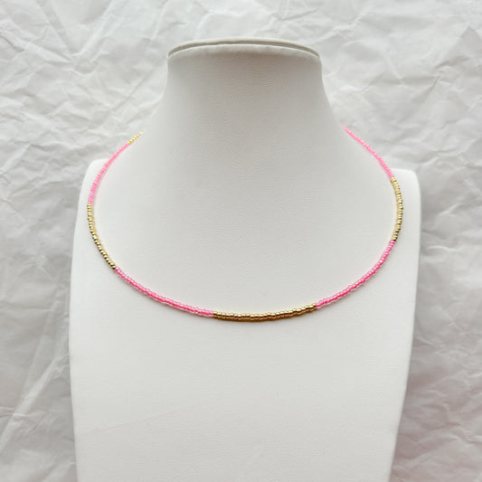 Collar Artesanal Gota con mostacillas en tonos rosa y dorado, exhibido sobre un busto blanco.