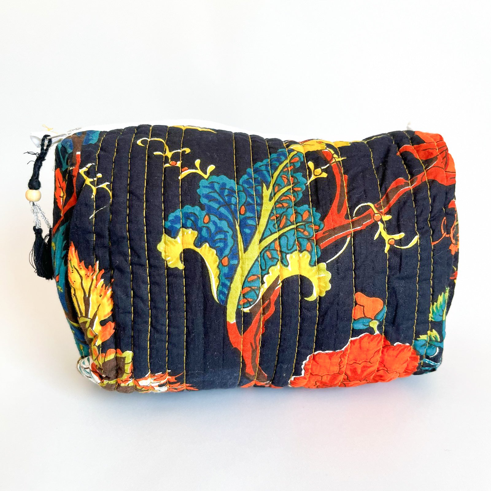 Estuche Bromelia acolchado con estampado floral colorido sobre base oscura, con detalles de borla y madera.