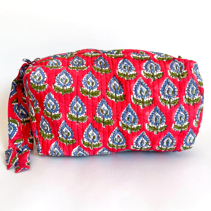 Estuche acolchado en tonos rojos y azules con estampado botánico y cierre con borla decorativa.