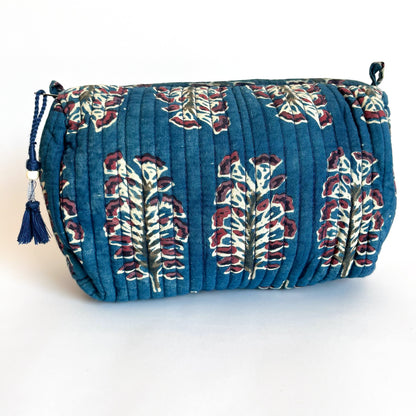 Estuche acolchado con estampado floral en tonos azul profundo y bordó sobre fondo oscuro, con borla decorativa en el cierre.