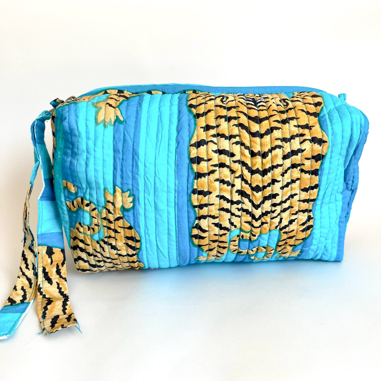 Estuche acolchado con estampado de tigres dorados sobre fondo azul vibrante, ideal para organizar cosméticos y accesorios con un diseño exótico y sofisticado.