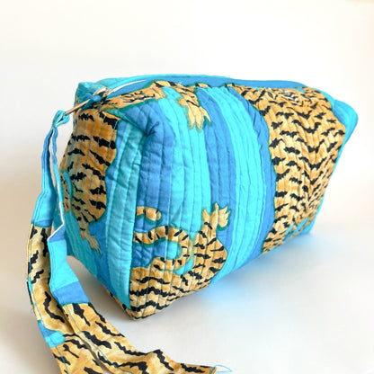 Estuche acolchado con estampado de tigres dorados sobre fondo azul vibrante, ideal para organizar cosméticos y accesorios con un diseño exótico y sofisticado.