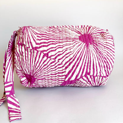 Estuche acolchado con diseño geométrico en tonos magenta y blanco, perfecto para organizar cosméticos y accesorios con un toque moderno.