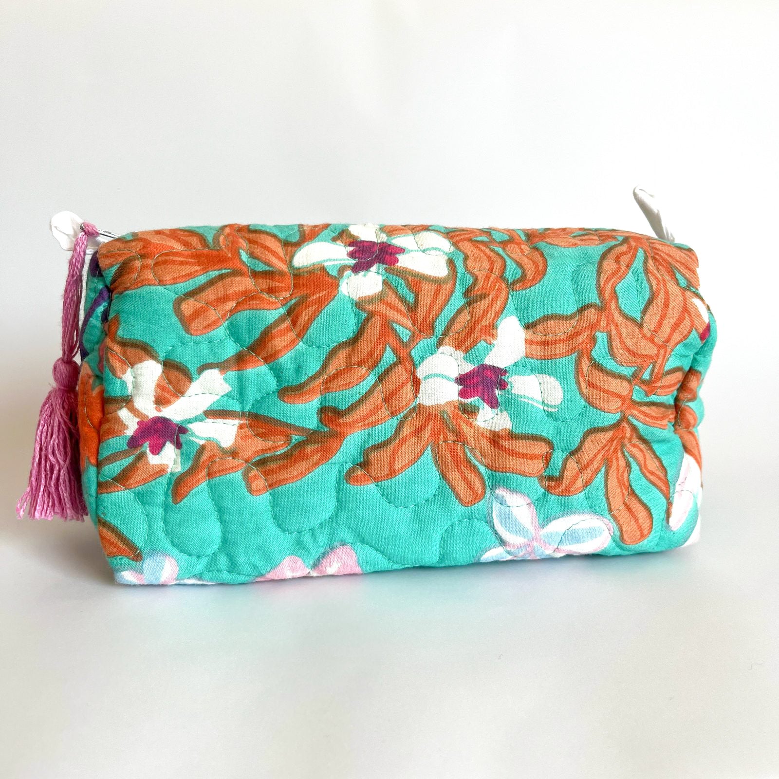 Estuche acolchado con estampado floral en tonos verdes, naranjas y fucsia, con borla decorativa en el cierre
