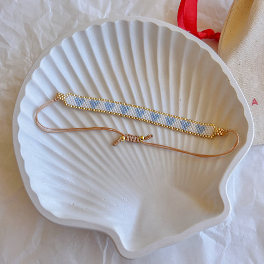 Pulsera Artesanal Corazones Josefina en azul celeste y dorado, con un diseño sutil.